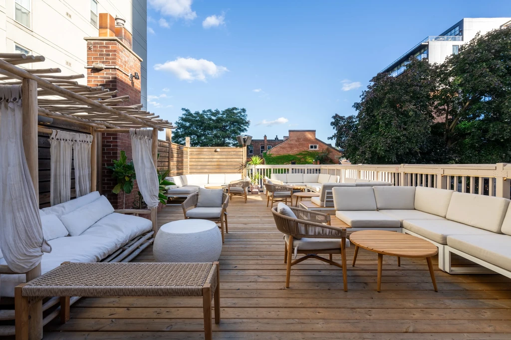 Rooftop patio with modern outdoor furniture, a pergola, and wooden decking.