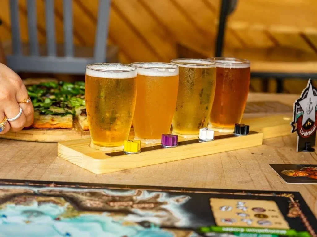 Four different beers, pizza, and a board game setup.