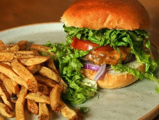 Gourmet burger with cheese, lettuce, tomato, and thick-cut fries.