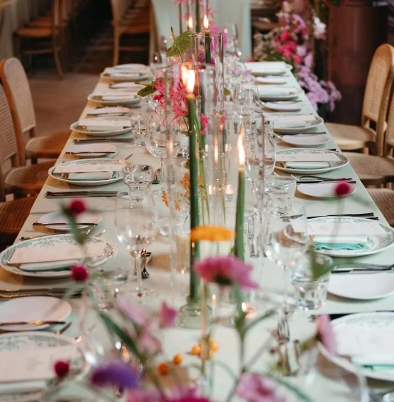 Candlelit dining table with plates, glasses, and floral centerpieces.