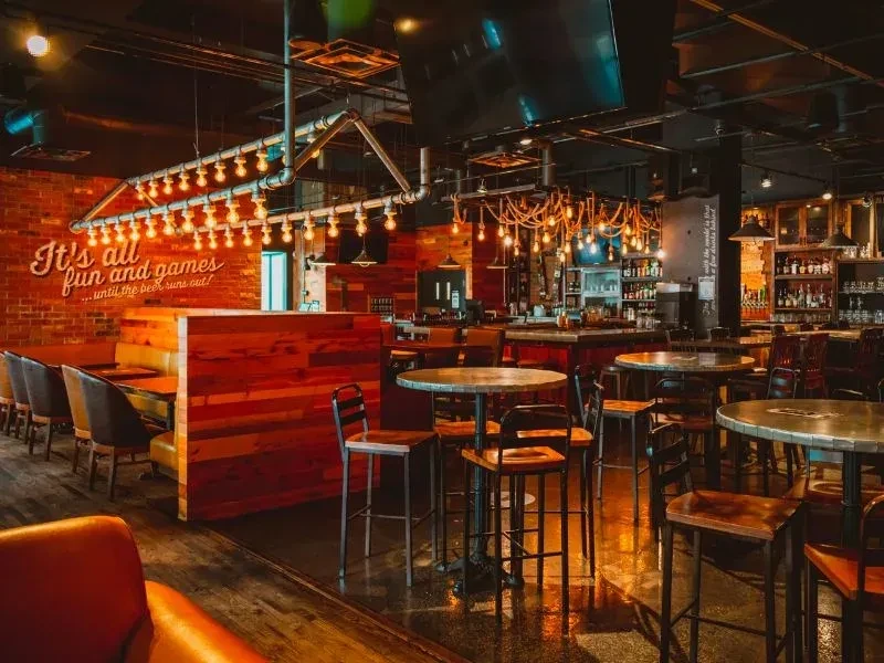 Warm industrial bar with Edison lights and 'beer runs out' wall text.