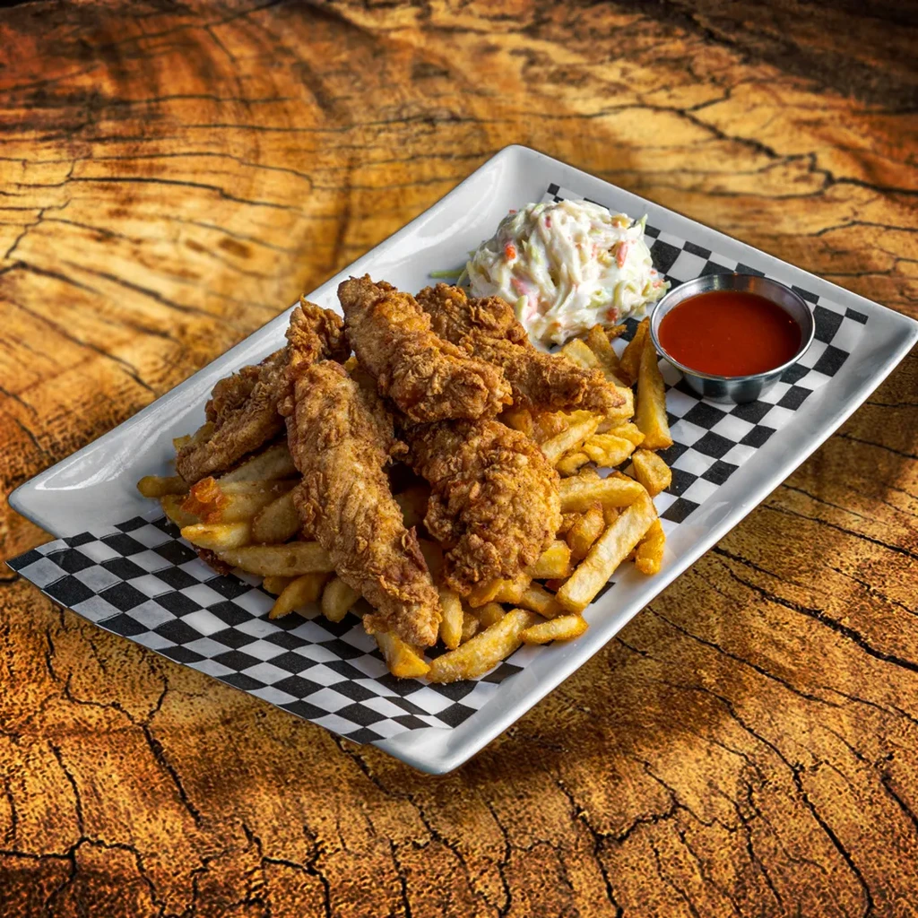 Plate of crispy chicken tenders, fries, coleslaw, and red dipping sauce.