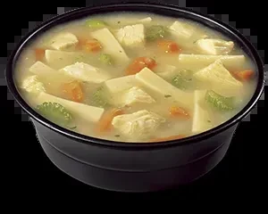 Creamy yellow soup in black bowl with chicken, noodles, broccoli, carrots.