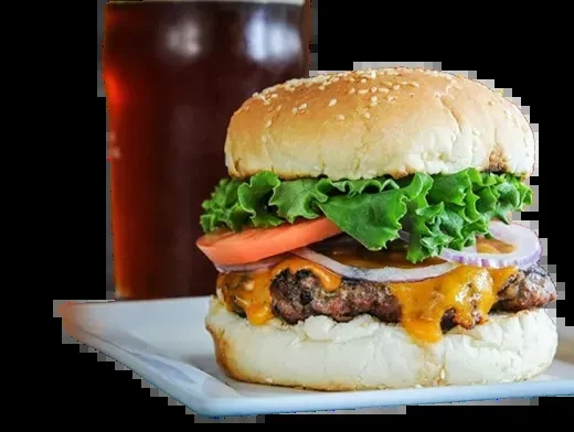 Close-up of a cheeseburger with melted cheddar, lettuce, tomato, and onions.