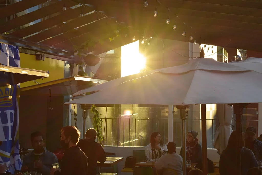 Golden hour illuminates a lively outdoor bar and dining area.