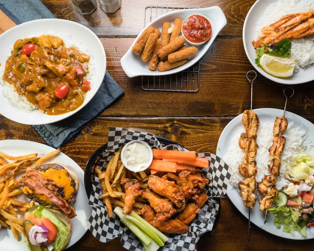 Overhead shot of rustic table laden with diverse restaurant dishes.