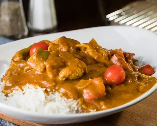 White rice topped with chicken curry, tomatoes, and green peppers.