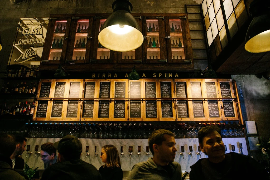 Rustic chalkboard beer menu and taps in a dimly lit bar.