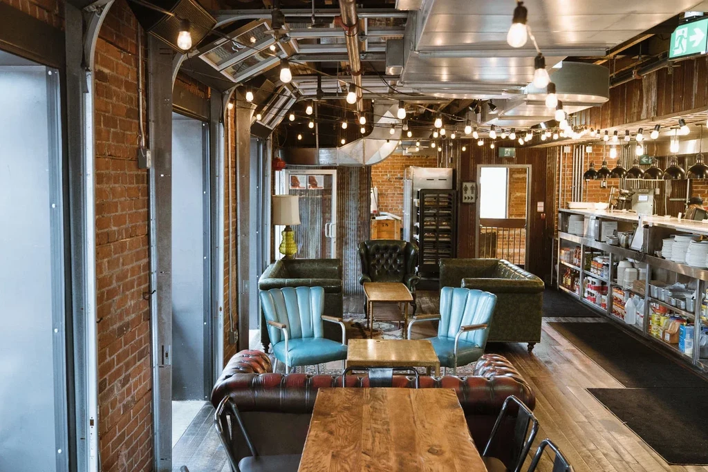 Industrial-chic restaurant interior with exposed brick, tufted seating, and bar.