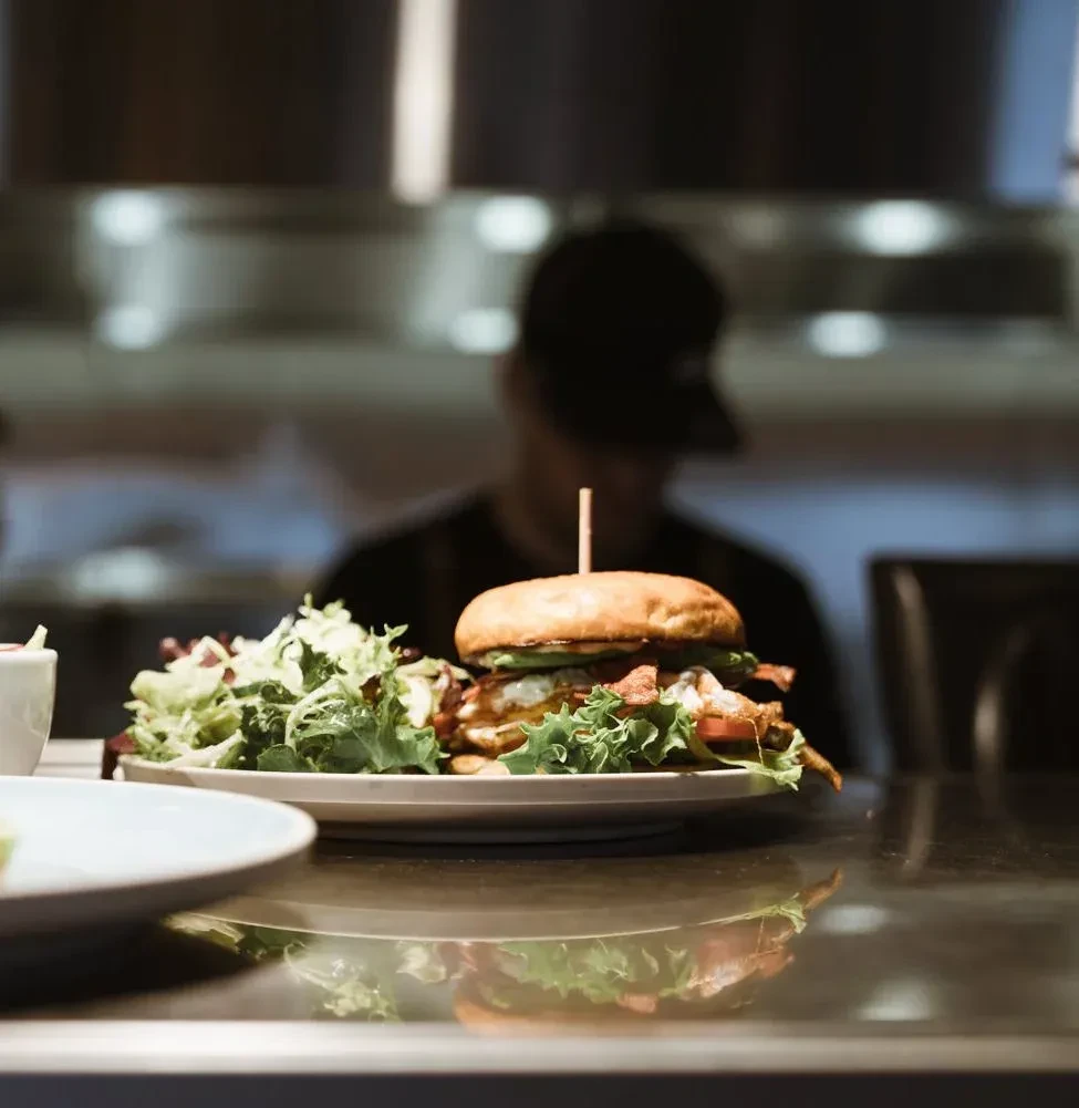 Gourmet burger and fresh salad on a white plate.