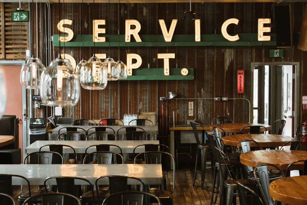 Industrial-chic restaurant interior with metal walls, pendant lights, 'SERVICE DEPT.' sign.