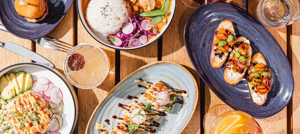 Overhead view of several colorful dishes and drinks on a wooden table.