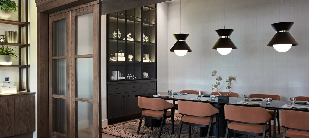 Modern private dining room with long table, rust chairs, and pendant lights.