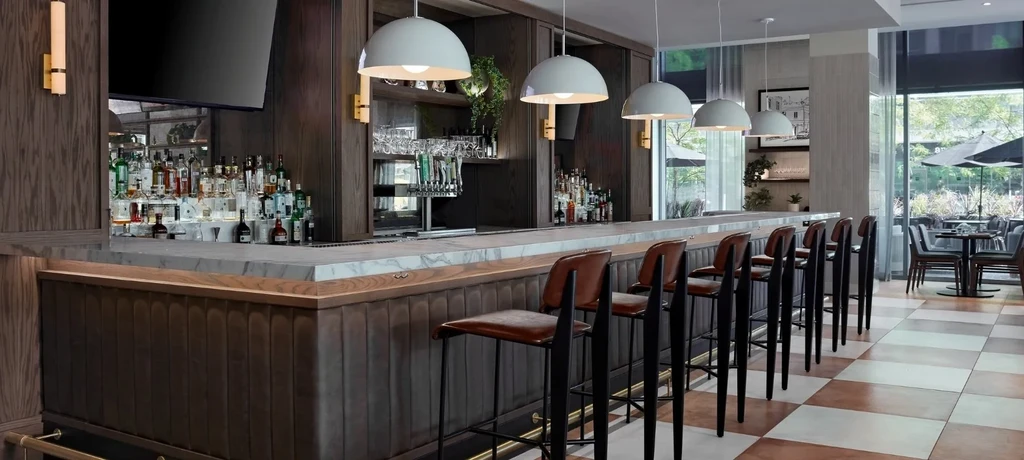 Modern bar area with marble counter, stocked back bar, and checkerboard floor.