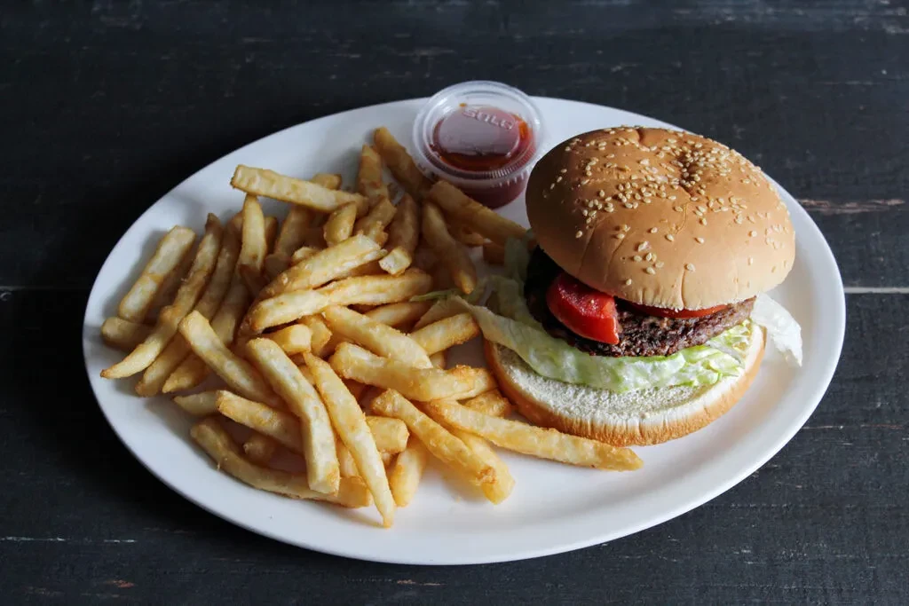 Plate of classic beef burger, golden fries, and ketchup.