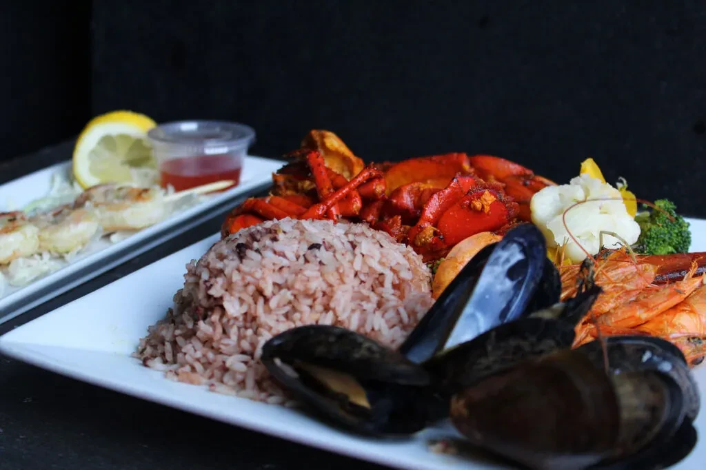 Large seafood platter with lobster, shrimp, mussels, rice, and vegetables.