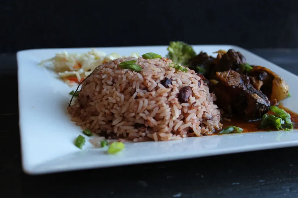 Plate of rice and beans, dark stewed meat, coleslaw, and broccoli.