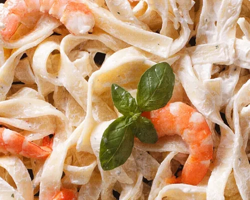 Tagliatelle pasta with creamy white sauce, shrimp, and basil.