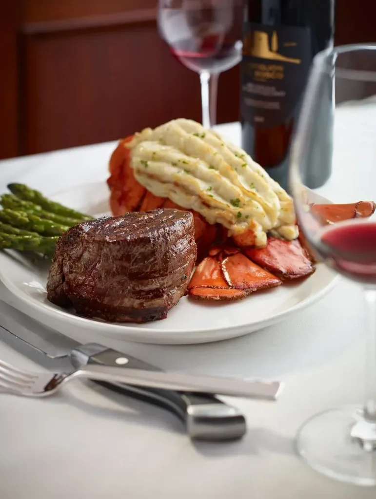 Plated surf and turf: grilled steak, lobster, asparagus, and red wine.