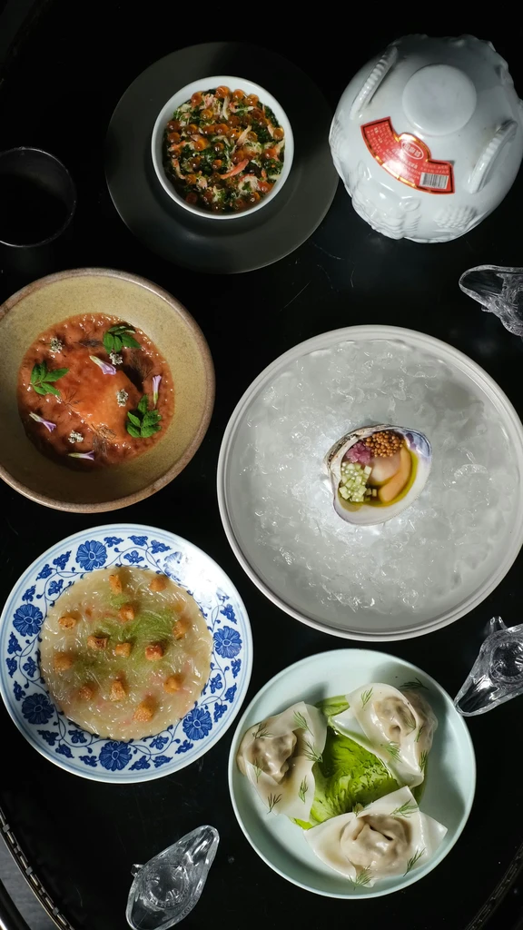Top-down view of six intricately plated gourmet dishes on a dark table.