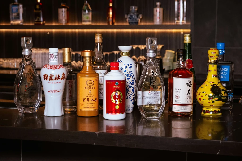 Various Chinese liquor bottles displayed on a dark, reflective bar.