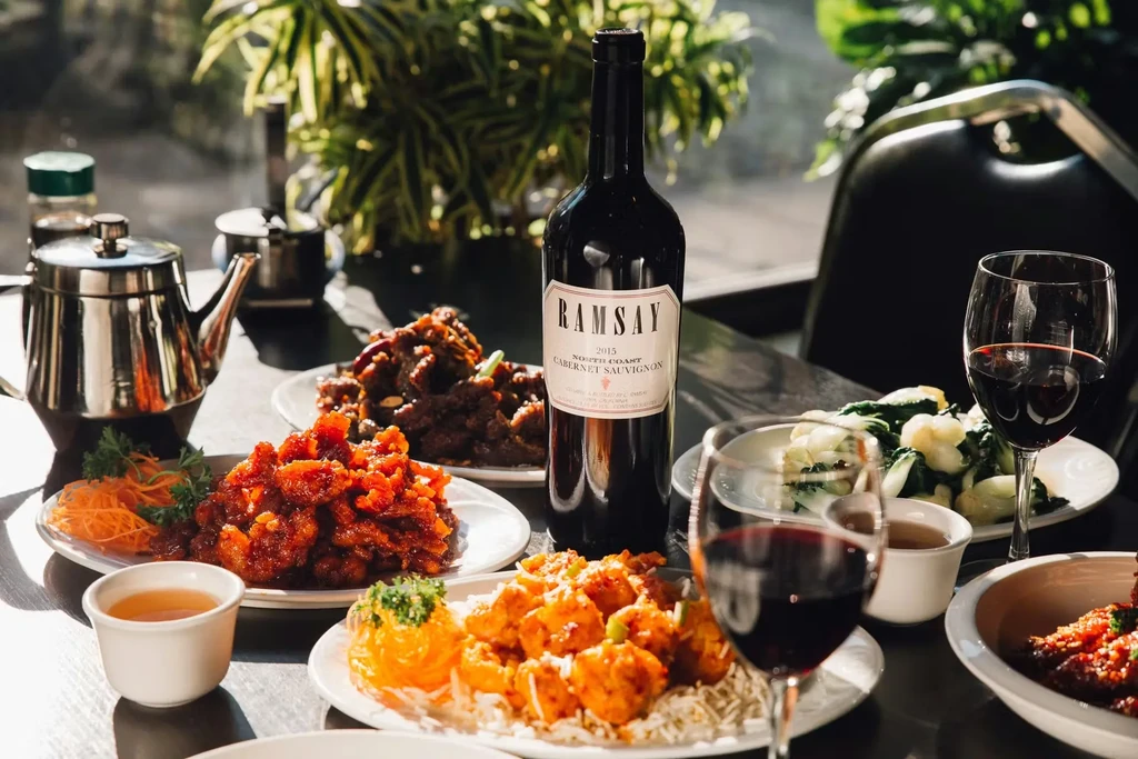 Close-up of Asian food, wine, and tea on a restaurant table.