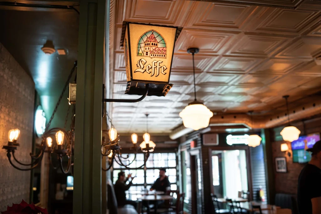 Cozy pub interior with an illuminated Leffe beer sign overhead.