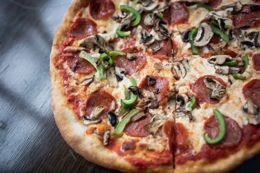 Overhead view of sliced pizza with pepperoni, mushrooms, bell peppers, cheese.