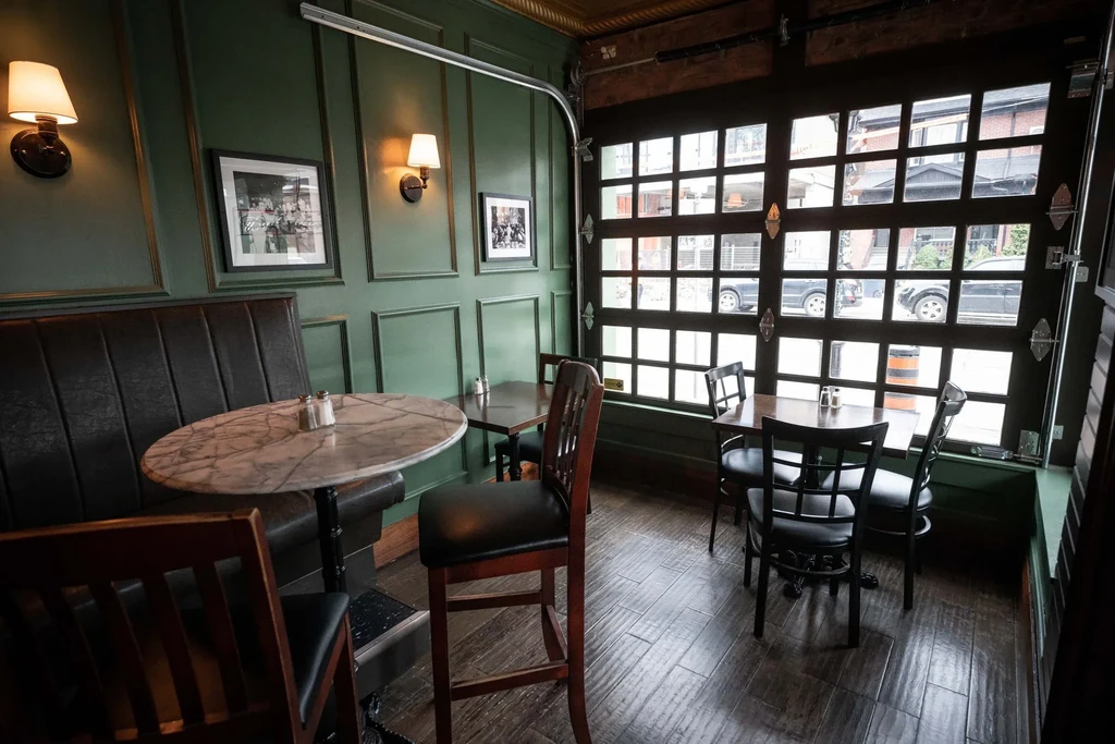 Restaurant interior featuring a leather booth, marble table, and large window.