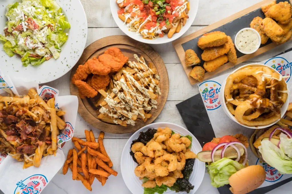 Overhead flat lay of diverse fried foods, salad, and a burger.