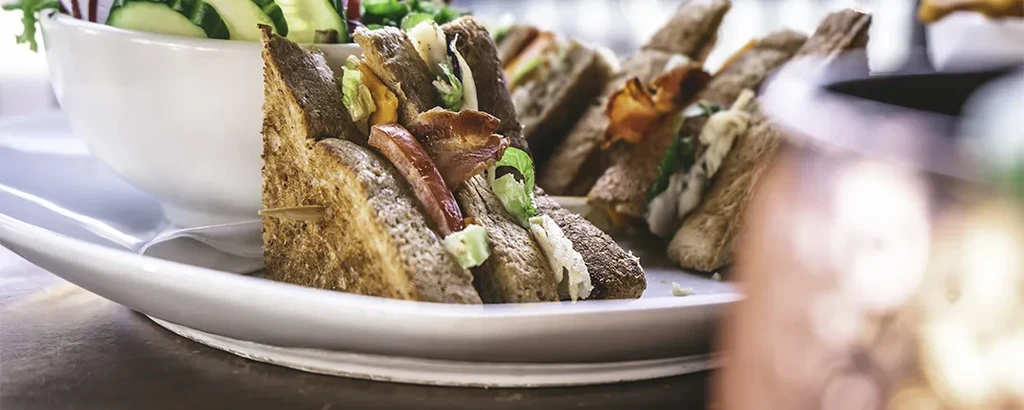 Whole-grain club sandwich with bacon, lettuce, and a side salad.