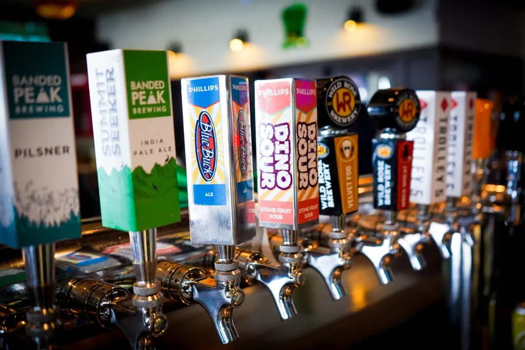 Close-up of various craft beer tap handles in a row at a bar.