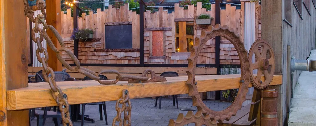 Rustic industrial decor with rusty chains, a gear, and wooden beam.