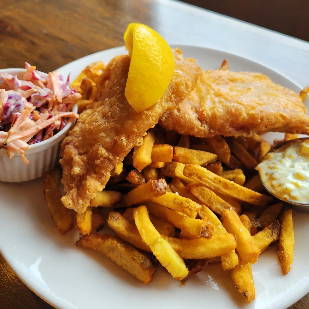 Plate of fish and chips with lemon, coleslaw, and tartar sauce.