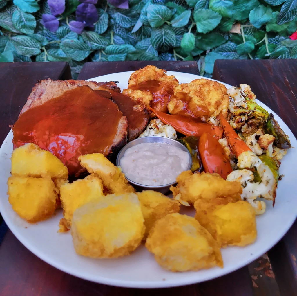 Roasted meat with gravy, roasted vegetables, and fried potatoes.