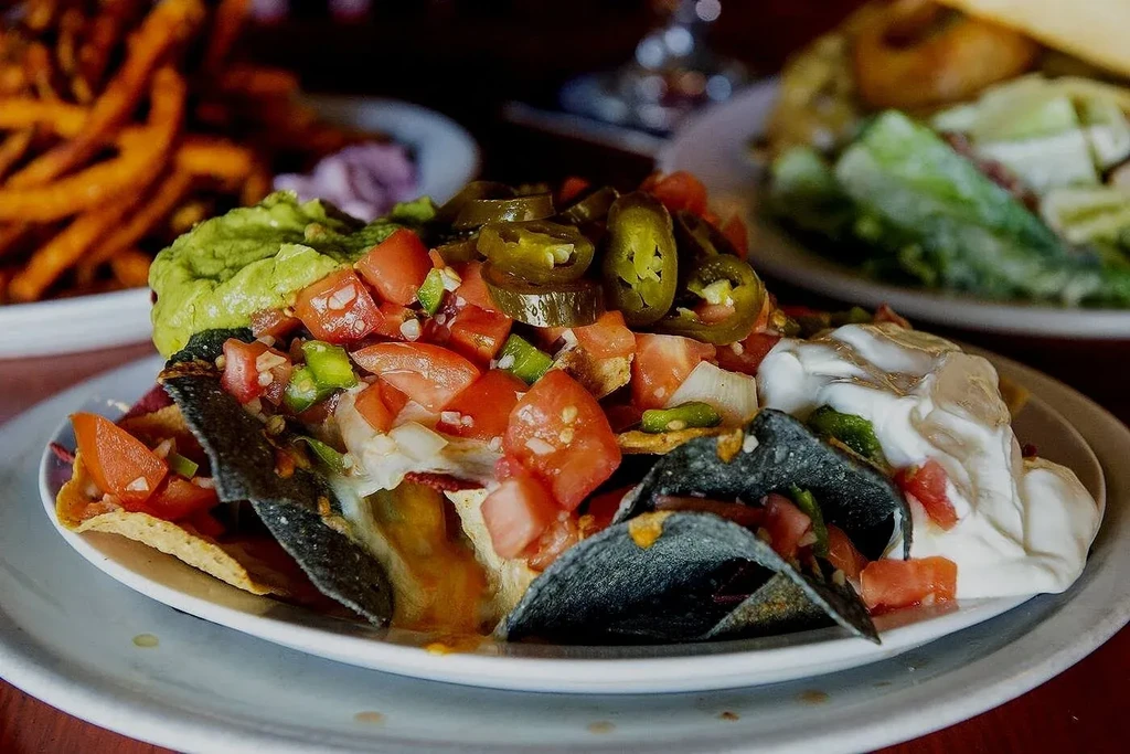 Loaded nachos with guacamole, sour cream, tomatoes, and jalapeños.