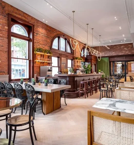 Empty stylish restaurant interior featuring a bar, brick walls, and diverse seating.
