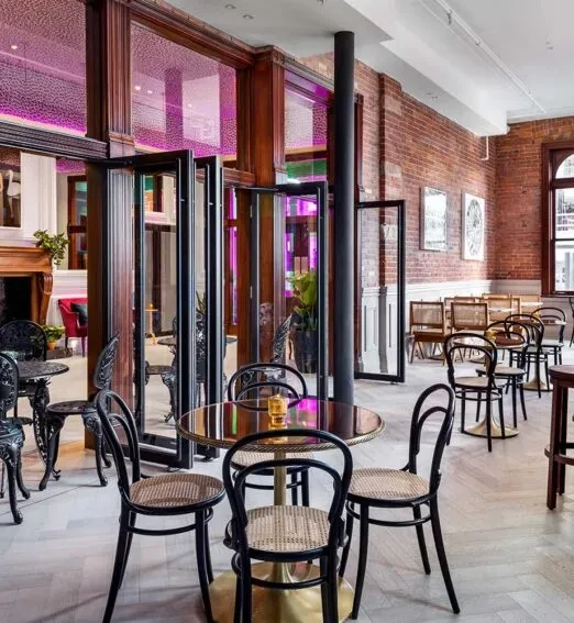 Modern restaurant interior featuring purple-magenta lit glass partitions and stylish seating.