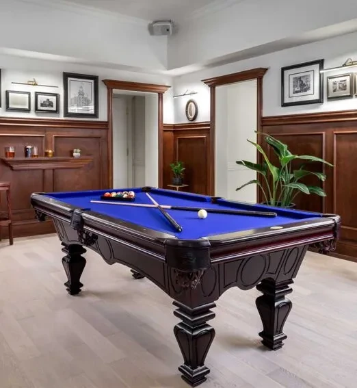 Ornate blue felt billiards table in a sophisticated wood-paneled room.