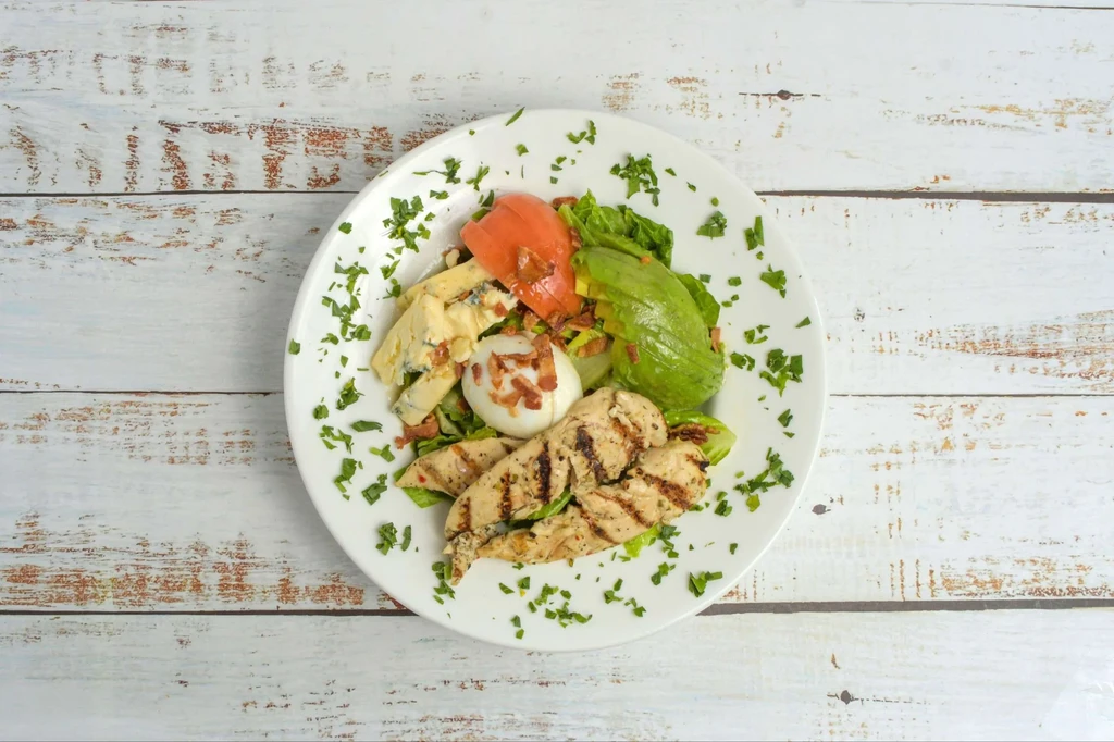 Grilled chicken salad with avocado, blue cheese, egg, and tomato.