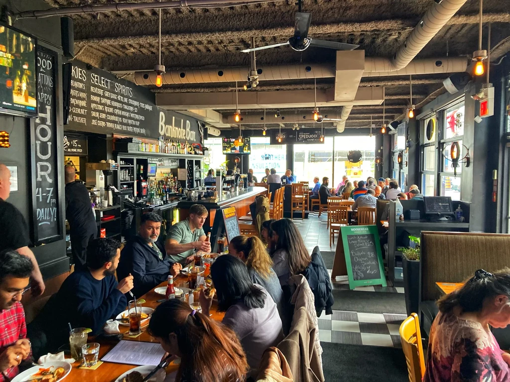 Bustling industrial-style restaurant and bar interior with patrons.