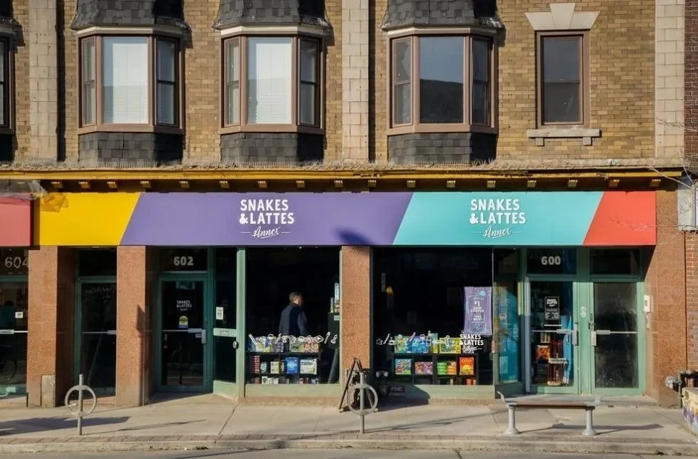 "Snakes & Lattes" cafe's colorful awning and brick storefront.