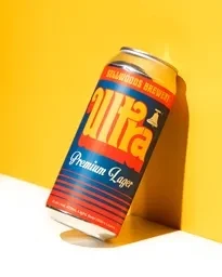 Blue and orange "Ultra" lager can against a yellow background.