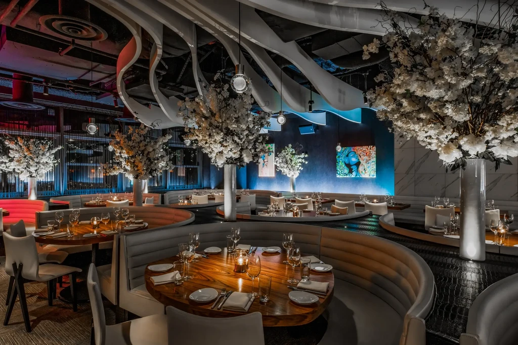 Empty, modern restaurant interior with tables, booths, and cherry blossom flowers.