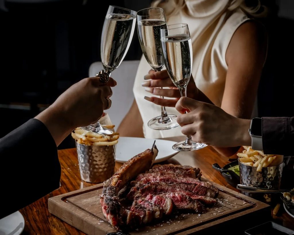 Upscale dining with steak, fries, and a celebratory champagne toast.