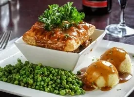 Savory pie with golden crust, mashed potatoes, peas, and gravy.