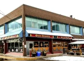 Corner brick building, Queen Victoria's Pub & Restaurant, with patio and snow.