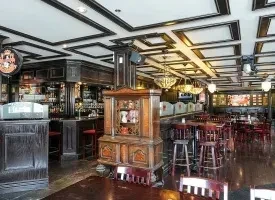 Traditional dark wood pub interior with bar, dining area, and coffered ceiling.