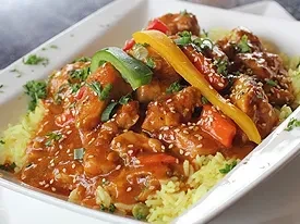 Chicken and yellow rice with reddish-orange sauce and vegetables.