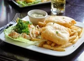 Golden-brown fish and chips with seafood salad and dipping sauce.